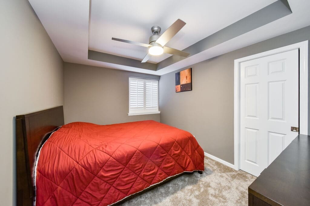 Cozy guest bedroom with tray ceiling and modern fan