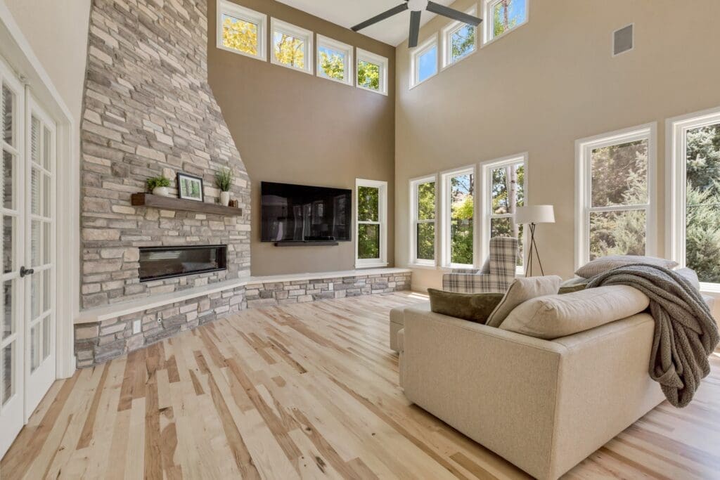Modern living room with stone fireplace, high ceilings, and wall-mounted TV