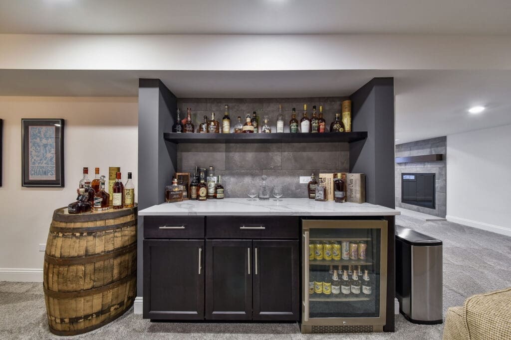 Basement whiskey bar with dark cabinetry and marble counters