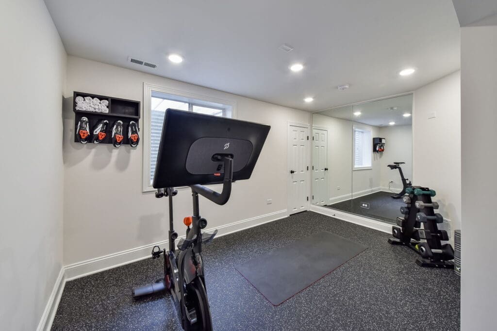 Modern home gym with Peloton bike and mirrored wall