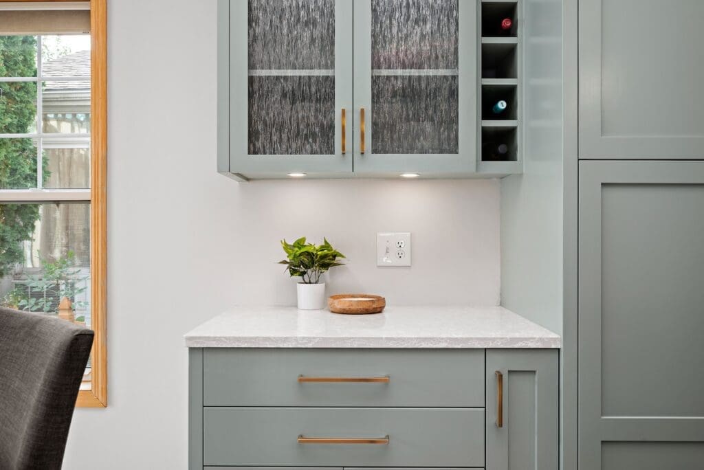 Built-in wet bar with sage green cabinetry and wine storage