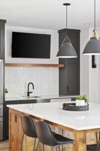 Modern basement kitchenette with white hex tile backsplash, matte black fixtures, and pendant lighting over island