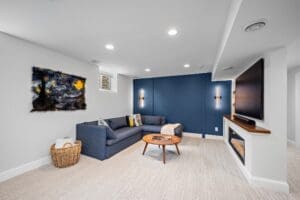 Basement living area with navy accent wall, electric fireplace, and large sectional sofa
