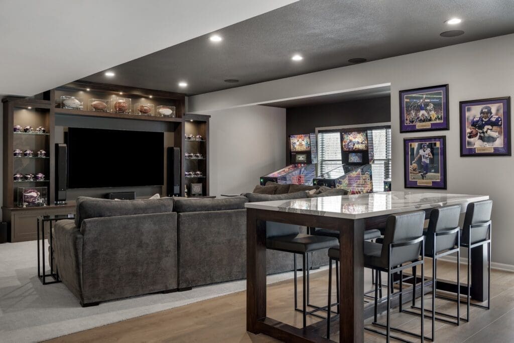 Basement entertainment space with sectional, arcade machines, and sports memorabilia