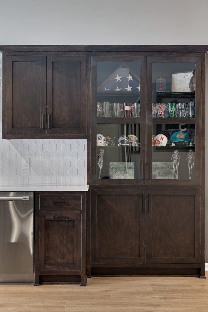 Dark wood built-in cabinet with glass display of trophies, flags, and memorabilia