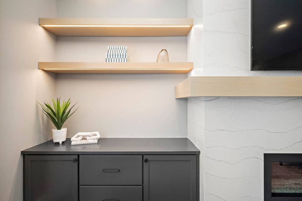 Minimalist built-in with light wood floating shelves, matte black cabinet, and soft lighting