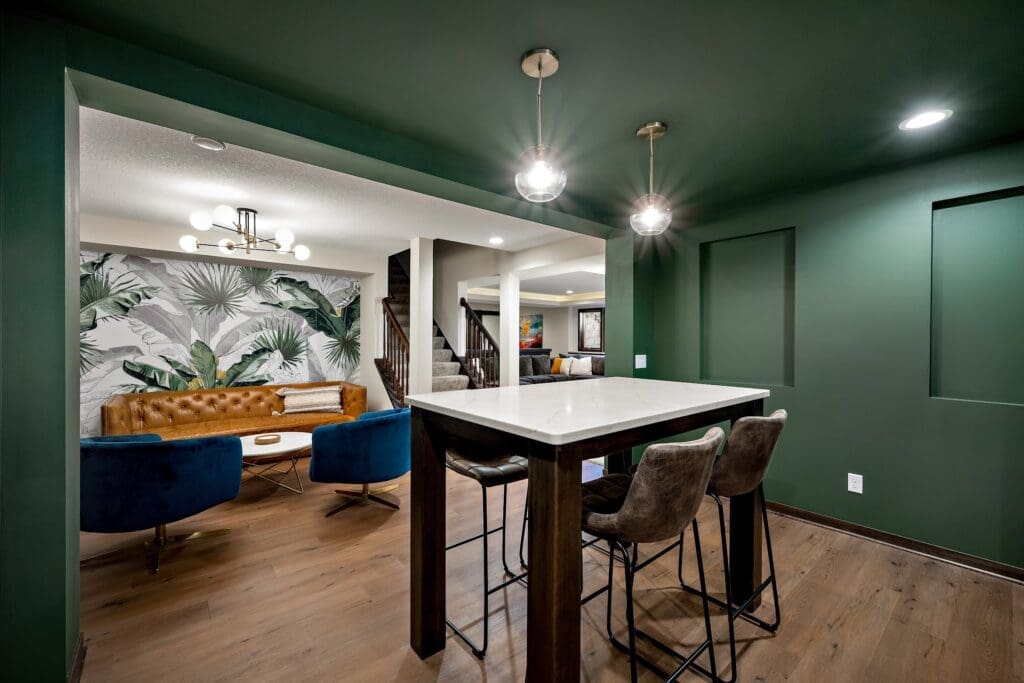 Moody green basement lounge with accent wall, pendant lighting, and tropical mural