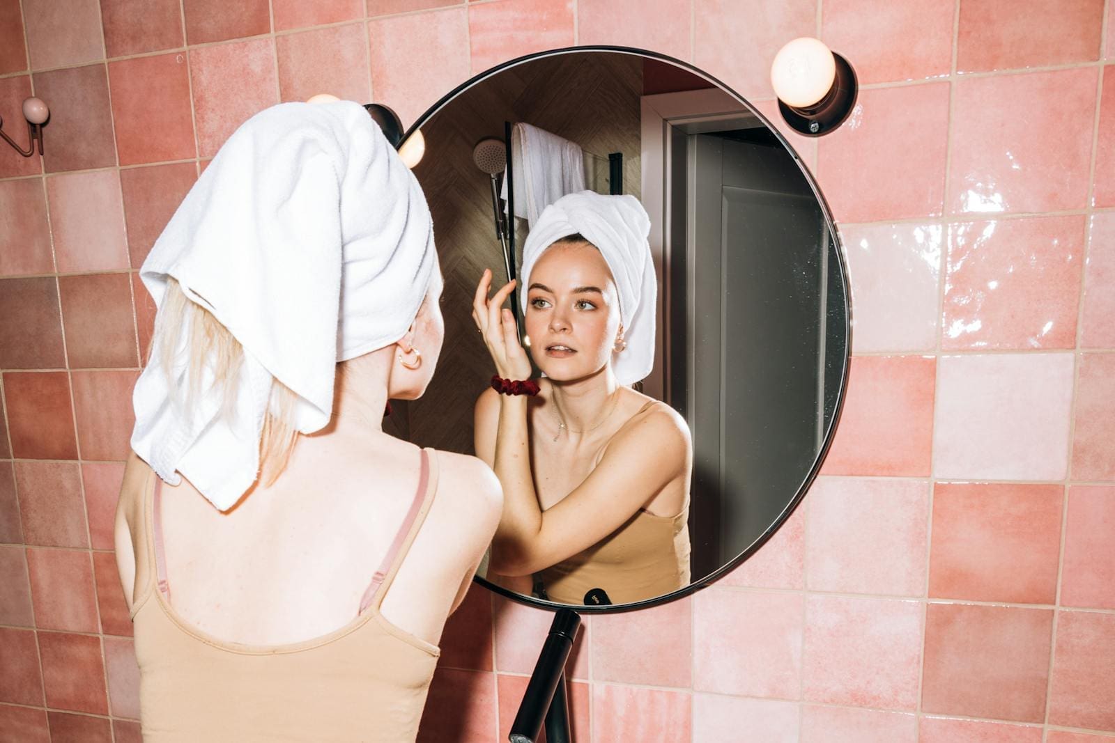 A girl looking into the bathroom mirror after a shower.